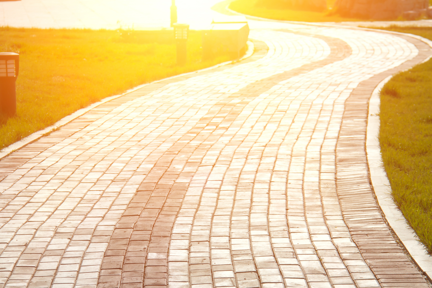 A brick path winding through a park, with sunlight shining brightly. The image might evoke feelings of warmth, peace, and the beauty of nature.