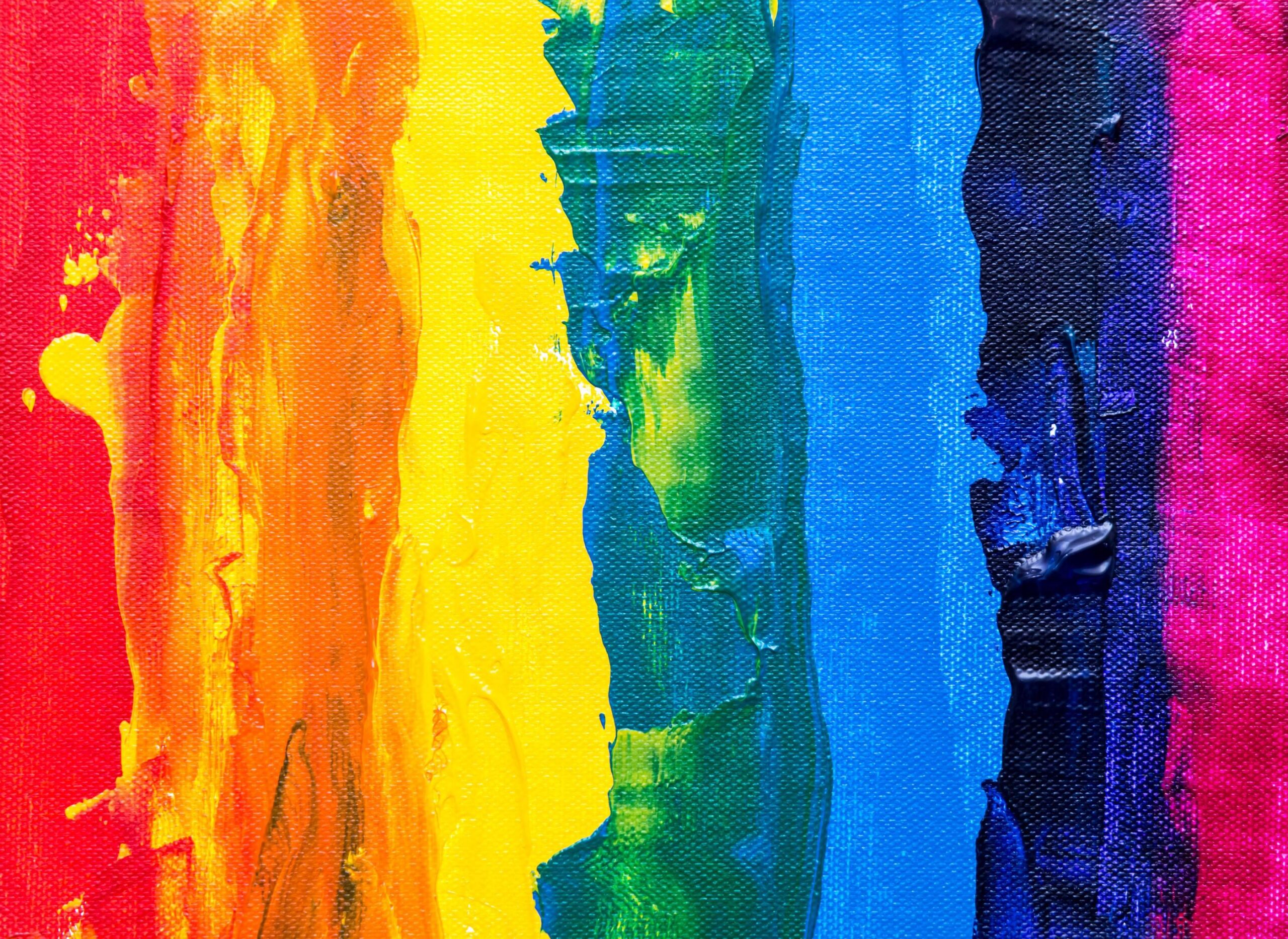 A vibrant abstract painting features bold, textured vertical stripes in the colors of the rainbow: red, orange, yellow, green, blue, and violet. The rich, layered application of paint on a canvas gives the piece a dynamic, tactile quality, celebrating diversity and inclusion. The colors blend subtly at the edges, creating an organic, harmonious flow.