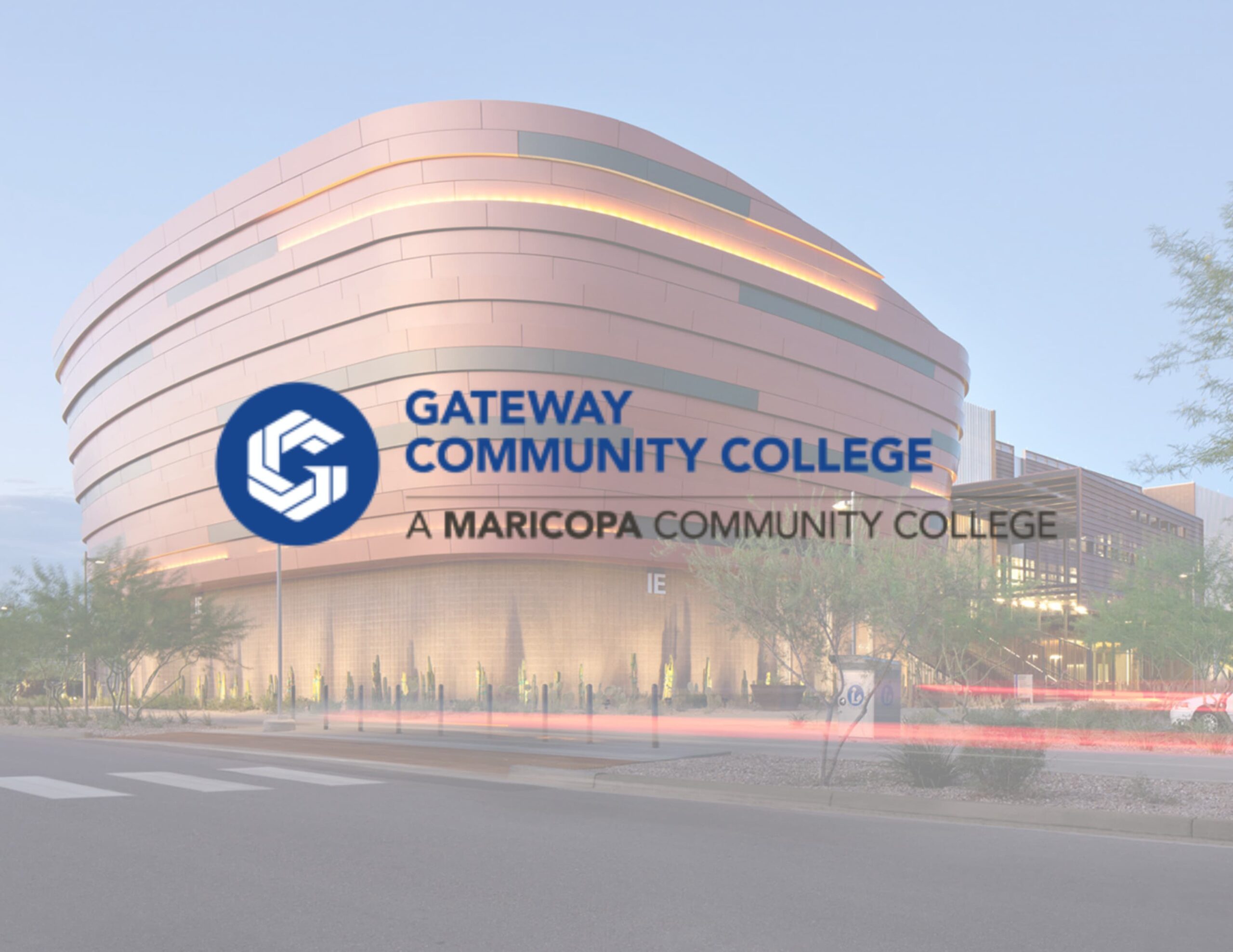 A modern building with sleek, curved architecture is prominently displayed in the background, lit warmly in the early evening. Overlaid text reads "Gateway Community College" in bold blue font with the tagline "A Maricopa Community College" below, accompanied by the Gateway logo featuring interlocking geometric shapes. The scene conveys a professional and welcoming atmosphere.