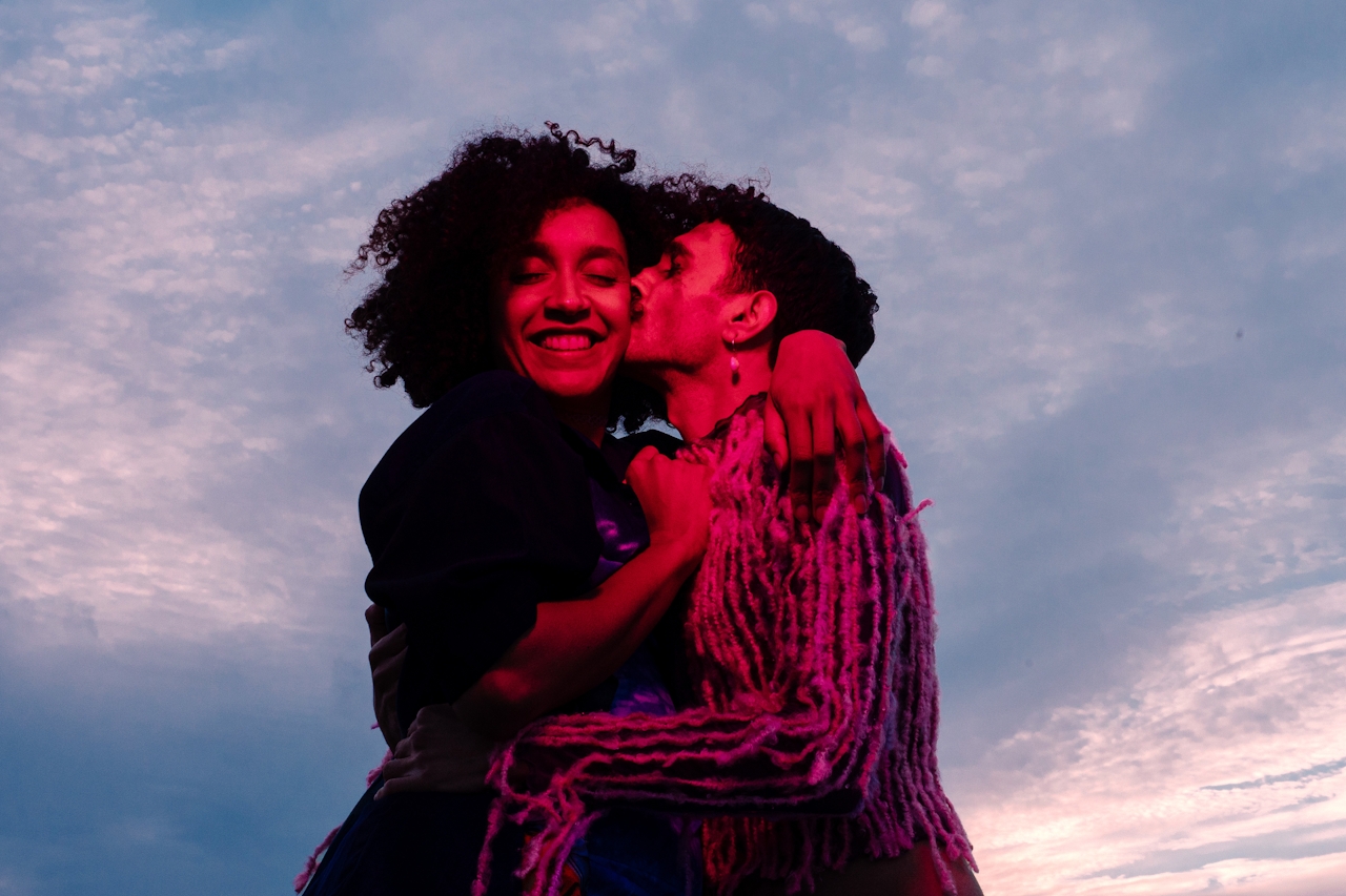 A happy couple embraces under a twilight sky.