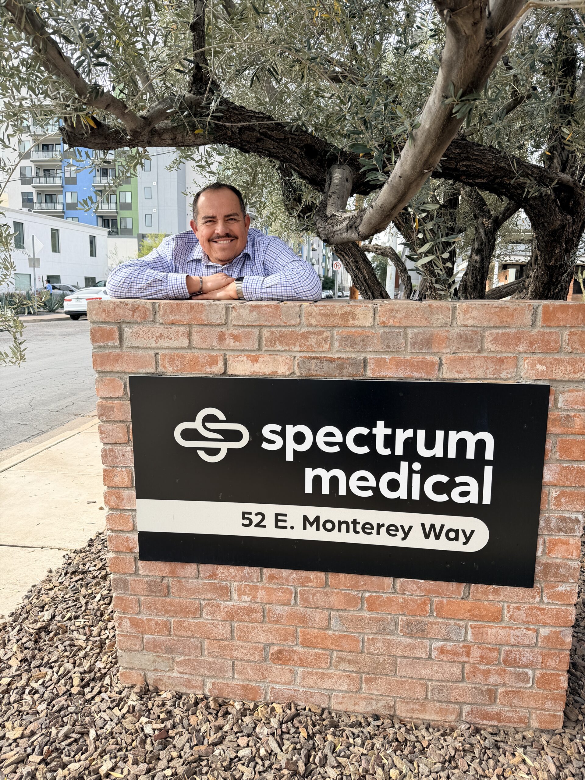 Ray Delgado smiles brightly as he poses next to Spectrum Medical's street sign.