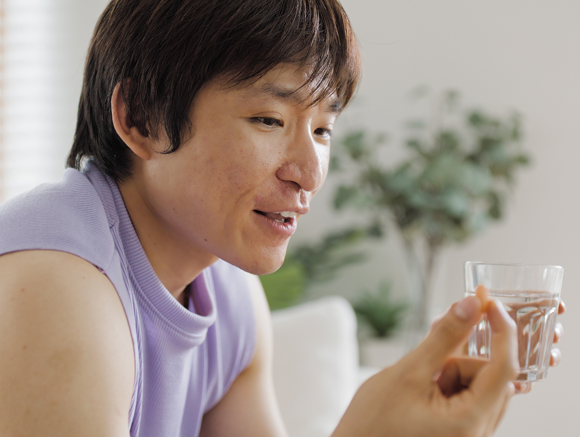 A person holds a glass of water about to take their medication.