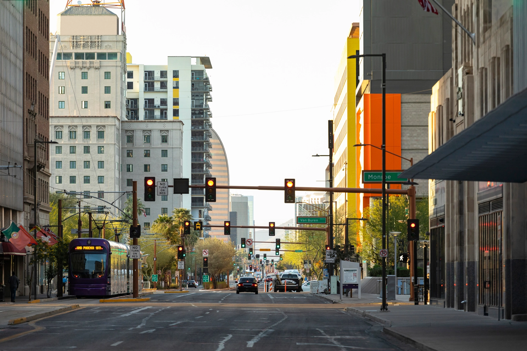 A view from the middle of the street in downtown Phoenix looking at a series of traffic lights.