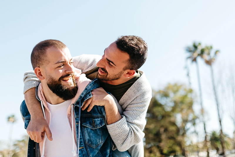 Two men smile at each other as they embrace.