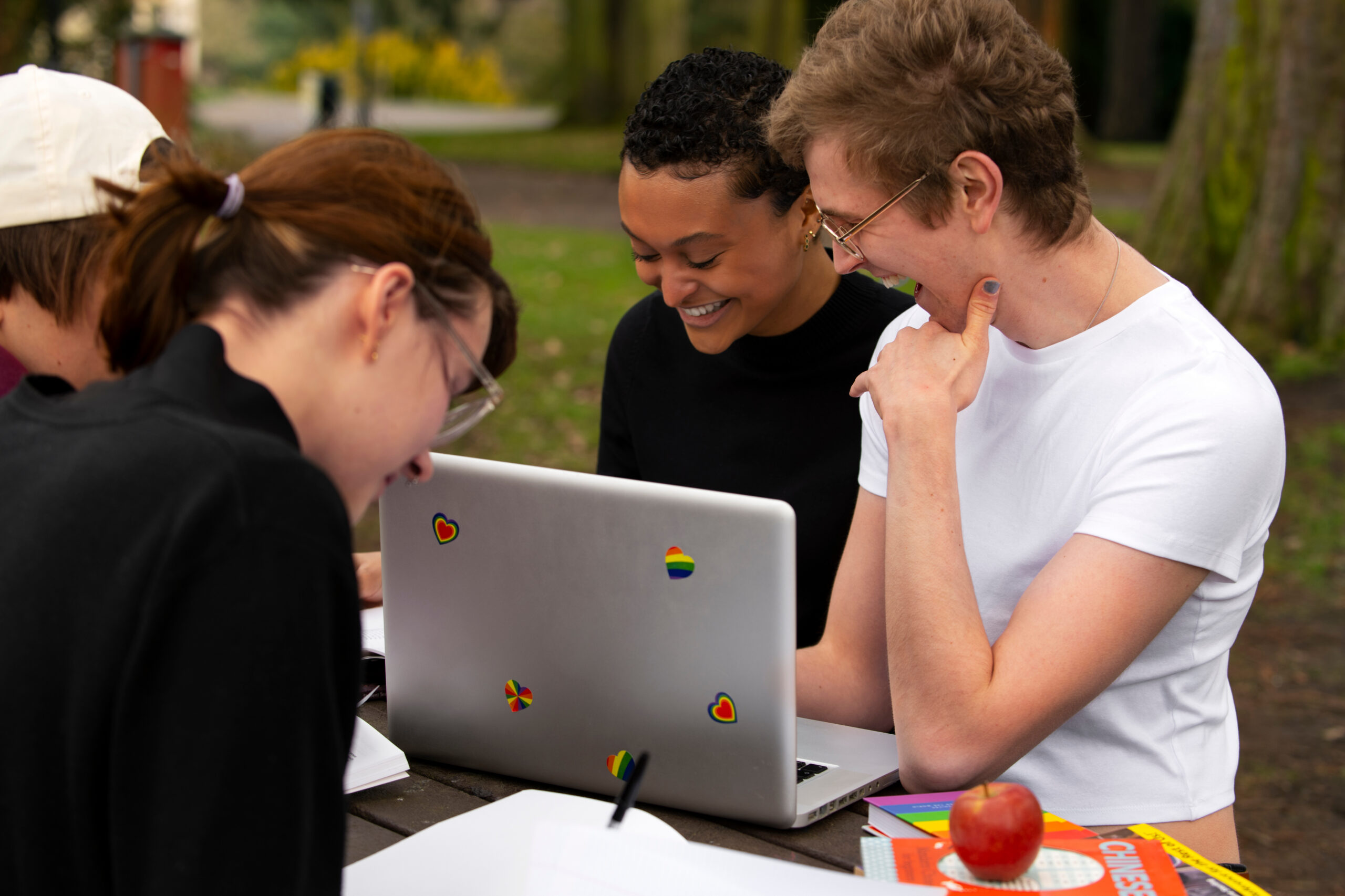 queer students gathered around a laptop smiling